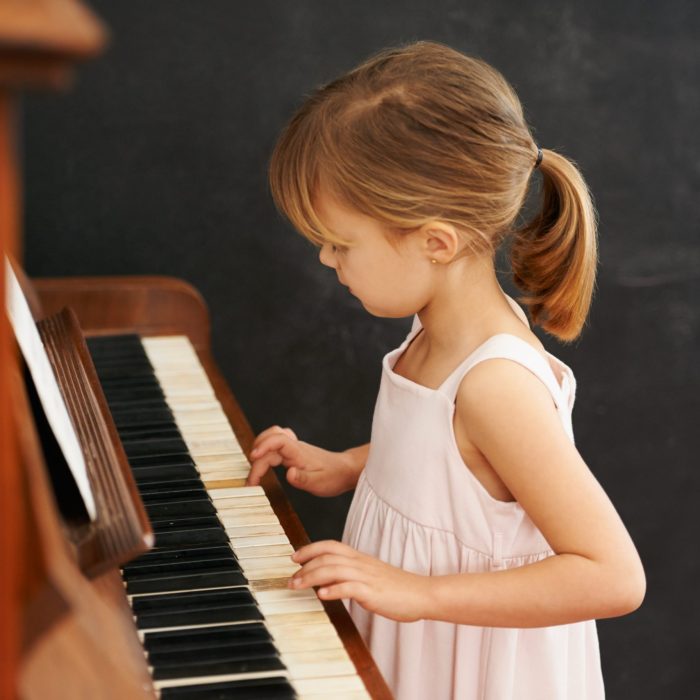 Piano, playing and kid in home for learning, practice and classical education with musical notes. Training, melody and girl with talent, creative or hobby with instrument, child development or skill.
